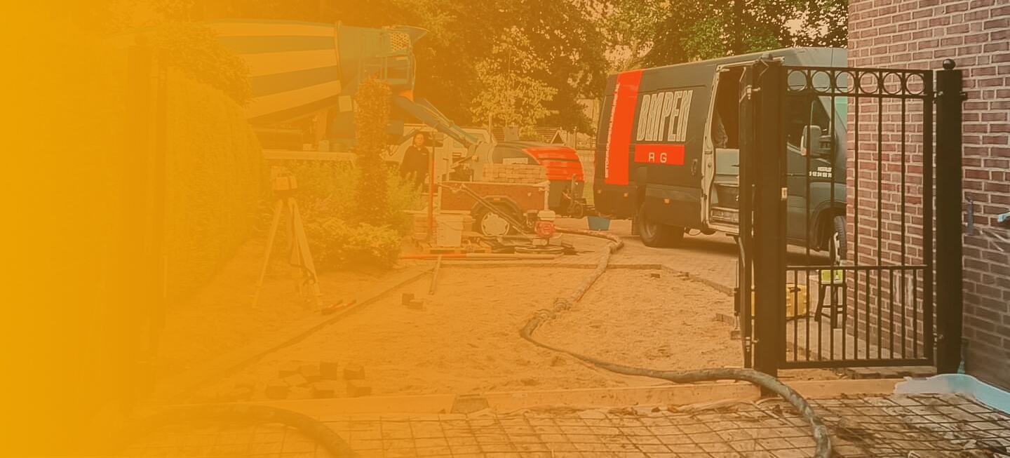 Betonpompslang door de poort naar de achtertuin bij het storten van een oprit